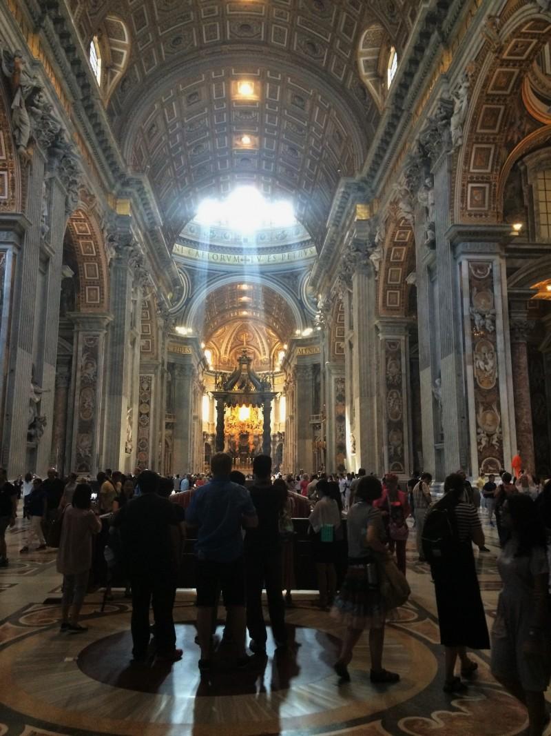 A view of the inside St. Peter's Basilica with Bernini’s baldachin illuminated by light coming in through the dome. Three cardinals were there giving mass and the smell of incense filled the massive basilica.  (Marcus Cirone / The DePaulia)