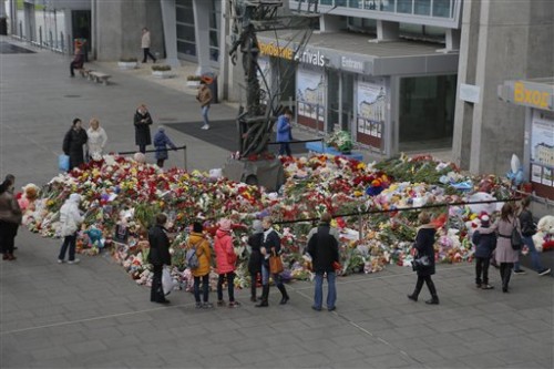 People stand near to floral tributes for the victims of a plane crash, at an entrance of Pulkovo airport outside St. Petersburg, Russia on Wednesday, Nov. 4, 2015. A Russian official says families have identified the bodies of 33 victims killed in Saturday's plane crash over Egypt. The Russian jet crashed over the Sinai Peninsula early Saturday, killing all 224 people on board. Most of them were holidaymakers from Russia's St. Petersburg. (AP Photo/Dmitry Lovetsky)