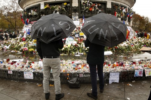Two men hold umbrellas that say "unite" while visiting a memorial site in Paris on Thursday, Nov. 19, 2015. (Carolyn Cole/Los Angeles Times/TNS)