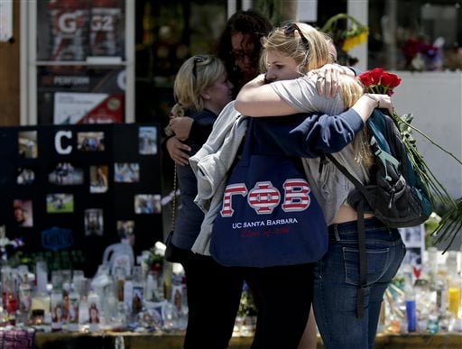 Mourners hug in front of the IV Deli Mart, where part of Friday night's mass shooting took place, on Tuesday, May 27, 2014 in the Isla Vista area near Goleta, Calif. Sheriff's officials said Elliot Rodger, 22, went on a rampage near the University of California, Santa Barbara, stabbing three people to death at his apartment before shooting and killing three more in a crime spree through a nearby neighborhood. (AP Photo/Chris Carlson)