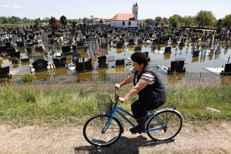A Bosnian woman cycles past a flooded cemetery in the village of Domaljevac near the Bosnian town of Orasje along the river Sava, 124 miles north of Sarajevo, Bosnia's capital. (AP Photo)