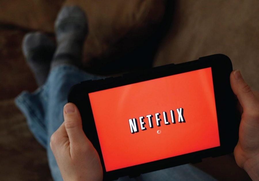 A person displays Netflix on a tablet. 