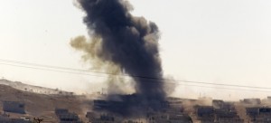 In this Oct. 6, 2014 file photo, smoke rises after a shell lands in Kobani in Syria as fighting intensifies between Syrian Kurds and the militants of Islamic State group, as seen from the outskirts of Suruc, at the Turkey-Syria border. After two months, the U.S.-led aerial campaign in Iraq has so far hardly dented the core of the Islamic State group’s territory. The extremists’ grip on major cities across Iraq and neighboring Syria remains unquestioned. The campaign has brought some gains, with Kurdish fighters taking back towns on the fringes of the Islamic State group’s territory. But those successes only underline a major weakness: Besides the Iraqi Kurds, there are no forces on the ground ready to capitalize on the airstrikes. (AP Photo/Lefteris Pitarakis)