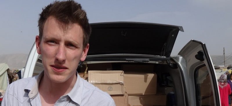 This undated photo provided by Kassig Family shows Peter Kassig standing in front of a truck filled with supplies for Syrian refugees. Confronted by terrorists beheading Americans, President Barack Obama has ordered a review of how the United States responds when citizens are taken hostage overseas. (AP Photo/Courtesy Kassig Family)