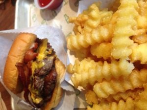 A Smoke Shack burger, loaded with bacon and cheese, with crispy crinkle cut french fries. (Maggie Gallagher / The DePaulia)