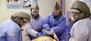 Medical workers wearing protective equipment surround a simulated patient during a demonstration for media members on their training for working with possible Ebola patients. (Elaine Thompson | AP)