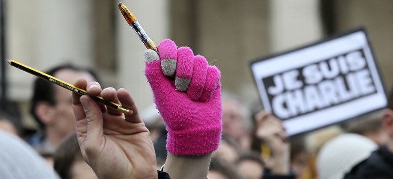 People hold up pens and pencils as they stand at a memorial gathering for the victims of the recent terrorist attacks in France at Trafalgar Square, London, on Jan. 11. (Tim Ireland | AP)