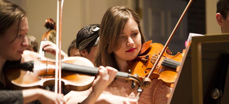 Katherine Baloff (right) performs with the DePaul Symphony Orchestra. The group rehearses three days a week for two hours, though only counts for one credit hour per quarter. (Kirsten Onsgard / The DePaulia)