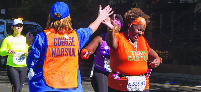 Nikki Carter, 42, of Chicago high fives a course marshall near mile 10 of the Bank of America Chicago Marathon. No matter the distance, it’s important to take time to train for races. (Courtney Jacquin / The DePaulia)