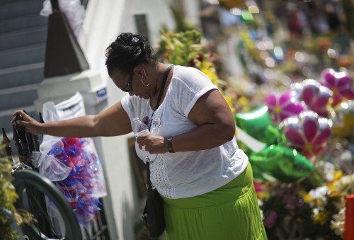 Terri Barr, of Columbia, S.C., stands silently against a fence while visiting a sidewalk memorial in memory of the shooting victims in front of Emanuel AME Church Monday, June 22, 2015, in Charleston, S.C. "It was just senseless and I just wanted to be here," said Barr. "It's sad. It's hurting, but you know, we'll heal." (AP Photo/David Goldman)