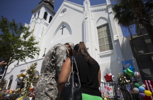U.S. Army Spc. Ron Leary, left and Astride Leary, of Savannah, Ga., pray at a sidewalk memorial in memory of the shooting victims in front of Emanuel AME Church, Monday, June 22, 2015, in Charleston, S.C. (AP Photo/David Goldman)