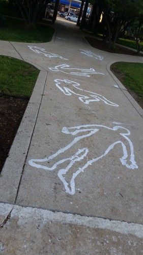 Chalk outlines, part of an artistic police brutality awareness display put on by Amnesty International at DePaul, line the sidewalks of the quad early Wednesday morning before washed away by request of Public Safety. 