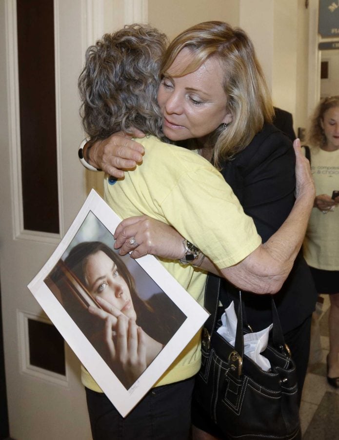 Debbie Ziegler holds a photo of her daughter, Brittany Maynard, as she receives congratulations from Ellen Pontac, left, after a right-to die measure was approved by the state Assembly. Wednesday, Sept. 9, 2015, in Sacramento, Calif. The bill, approved on a 42-33 vote, that would allow terminally ill patients to legally end their lives, now goes to the Senate. Brittany Maynard was the California woman with brain cancer  who moved to Oregon to legally end her life last fall. (AP Photo/Rich Pedroncelli)