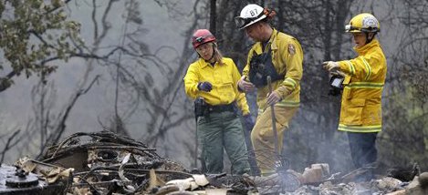 Firefighter Sean Norman, center, and search dog handlers Mary Cablk, left, and Lynne Engelbert look over the remains of a home in the Anderson Springs area of a man missing following a wildfire days earlier Wednesday, Sept. 16, 2015, near Middletown, Calif. Aided by drought, the flames have consumed more than 100 square miles since the fire sped Saturday through rural Lake County, less than 100 miles north of San Francisco. Cooler weather helped crews gain ground and the fire was 30 percent contained Wednesday. (AP Photo/Elaine Thompson)