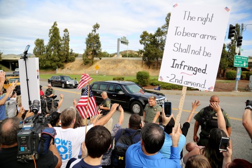 FILE - In this Oct. 9, 2015 file photo, demonstrators wave flags and signs as President Barack Obama's motorcade leaves Roseburg High School after a visit with families of victims of the shootings at Umpqua Community College in Roseburg, Ore. Voters in a southern Oregon county will weigh in next month on a measure that seeks to prohibit enforcement of gun laws, although it may have only symbolic effect. AP Photo/Ryan Kang, File)