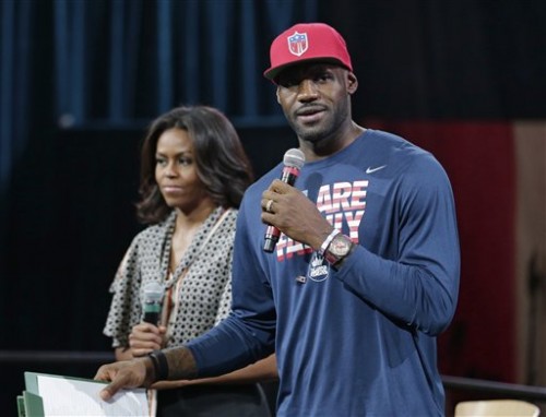 First lady Michelle Obama listens as Cleveland Cavaliers' basketball player LeBron James speaks to parents and children at The University of Akron, Wednesday, Oct. 21, 2015, in Akron, Ohio. James teamed up with Mrs. Obama to celebrate the importance of secondary education at a private event at the University of Akron. The NBA superstar, who went from high school to the pros, and first lady are hosting thousands of children and their parents at the school. (AP Photo/Tony Dejak)