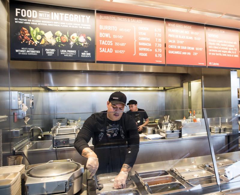 FILE - In this Dec. 15, 2015, file photo, a Chipotle Mexican Grill employee prepares food, in Seattle. After an E. coli outbreak that sickened more than 50 people, Chipotle is changing its cooking methods to prevent the nightmare situation from happening again. (AP Photo/Stephen Brashear, File)