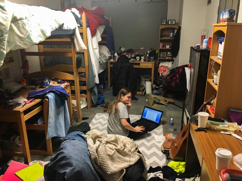 Lili Trifilio sits in the floor of her dorm in Clifton-Fullerton, whcih is meant for two but currently houses three people. (Revan Lowe-Watkins / The DePaulia)