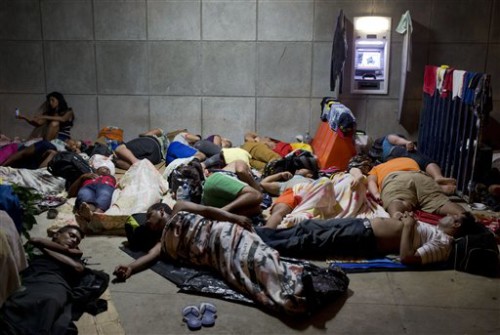 FILE - In this Nov. 21, 2015 file photo, a Cuban woman migrant uses her cell phone while other Cubans sleep, outside of the border control building in Penas Blancas, Costa Rica, on the border with Nicaragua which closed its borders to Cuban migrants. The Costa Rican Foreign Ministry said in a Dec. 28 statement that the first humanitarian transfer will airlift the Cuban migrants from that country to El Salvador in January. From there they will continue by bus toward Mexico. The number of Cubans stranded in Costa Rica has reached at least 8,000 since neighboring Nicaragua closed its border to them weeks ago.  (AP Photo/Esteban Felix, File)