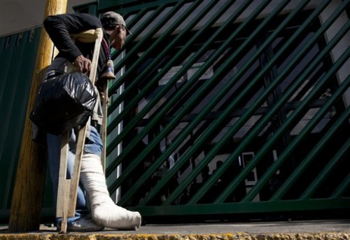 Wilmer Antonio Almendari a migrant from Honduras who broke his leg while riding the train through Mexico toward the U.S. border, waits outside the Agujas immigration detention center, in Mexico City, Tuesday, Jan. 5, 2016. Almendari says that he was riding the train known as "La Bestia" or "The Beast" as it rolled into Mexico City and was mugged and thrown off the the train. He broke his leg in the fall and was treated at a local hospital. He turned himself in, to Mexican immigration authorities and was asking for help to return back to his home country, Honduras. (AP Photo/Marco Ugarte)