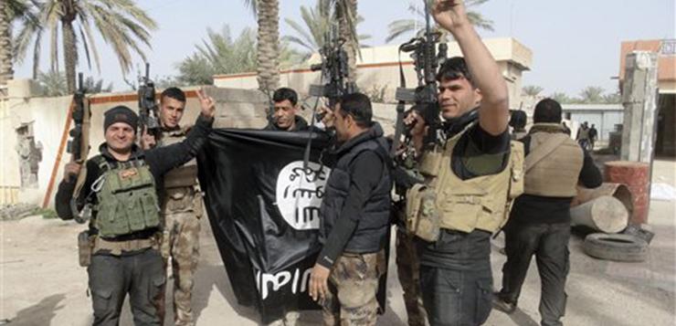 In this Tuesday, Jan. 19, 2016 photo, Iraqi security forces celebrate as they hold a flag of the Islamic State group they captured in Ramadi, 70 miles (115 kilometers) west of Baghdad, Iraq. The Islamic State group, which controls large parts of Syria and Iraq where it declared an Islamic caliphate in June 2014, suffered several defeats recently in both countries, including the loss of the Iraqi city of Ramadi and parts of northern and northeastern Syria over the past months. (AP Photo)
