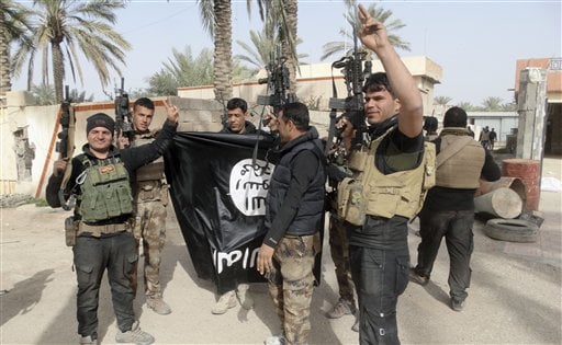 In this Tuesday, Jan. 19, 2016 photo, Iraqi security forces celebrate as they hold a flag of the Islamic State group they captured in Ramadi, 70 miles (115 kilometers) west of Baghdad, Iraq. The Islamic State group, which controls large parts of Syria and Iraq where it declared an Islamic caliphate in June 2014, suffered several defeats recently in both countries, including the loss of the Iraqi city of Ramadi and parts of northern and northeastern Syria over the past months. (AP Photo)