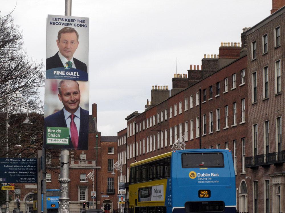 This photo taken Feb. 5, 2016, shows election posters of Prime Minister Enda Kenny, top, and Fianna Fail party leader Micheal Martin competing for space on a Merrion Square lamp post in Dublin, Ireland. Kenny hopes to keep his Fine Gael party in power following Ireland’s Feb. 26 election, but Martin’s opposition Fianna Fail, `Soldiers of Destiny’’ in Gaelic, has formed most governments since the 1930's. The party’s election slogan 'Eire do chach’ means 'Ireland for all.’(AP Photo/Shawn Pogatchnik)