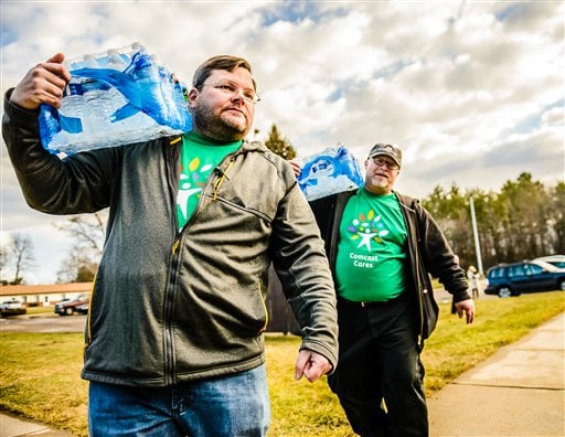 Michigan Representative Phil Phelps (D-Flushing), left, and Comcast employee Lloyd Richards deliver cases of water to residents at Slidell Senior Housing Saturday, Feb. 20, 2016 in Flint, Mich. (Kevin W. Fowler/AP Images for Comcast)