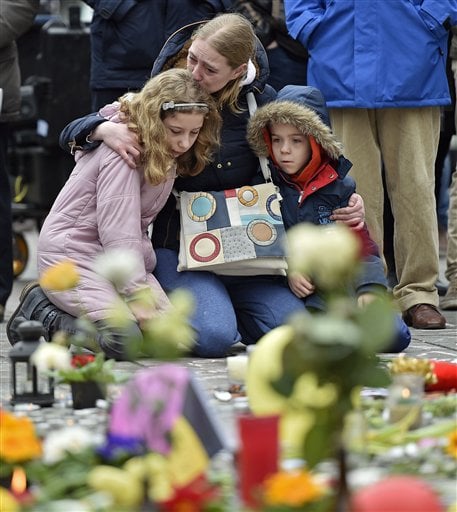 People mourn for the victims of the bombings at the Place de la Bourse in the center of Brussels, Wednesday, March 23, 2016. Bombs exploded yesterday at the Brussels airport and one of the city's metro stations Tuesday, killing and wounding scores of people, as a European capital was again locked down amid heightened security threats. (AP Photo/Martin Meissner)