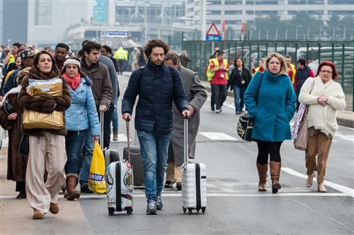 People walk away from Brussels airport after explosions rocked the facility in Brussels, Belgium Tuesday March 22, 2016.   Explosions rocked the Brussels airport and the subway system Tuesday, just days after the main suspect in the November Paris attacks was arrested in the city, police said. (AP Photo/Geert Vanden Wijngaert)