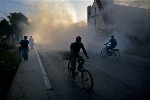 People make their way through fumigation fog, sprayed to kill Aedes Aegypti mosquitos, in Pinar del Rio, Cuba, Tuesday, March 1, 2016. Authorities are fumigating in an attempt to prevent the spread of Zika, Chikungunya and Dengue. (AP Photo/Ramon Espinosa)