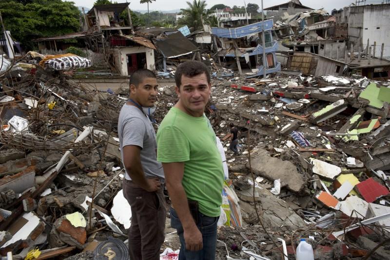 Neighbors watch a bulldozer demolish earthquake-damaged homes in Pedernales, Ecuador, Saturday, April 23, 2016. President Rafael Correa has said the earthquake caused $3 billion in damage and warned that the reconstruction effort will take years. His administration is temporarily raising taxes to fund the recovery. (AP Photo/Rodrigo Abd)