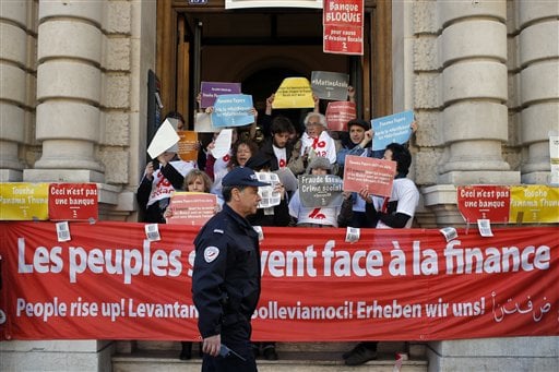 French police officer walks by as anti-fraud activists are blocking entrances at Societe Generale's Paris headquarters as part of a protest accusing the French bank of ties to the so-called "Panama Papers" in Paris, France, Thusday, April 7, 2016. Societe Generale denies any accusations of fraud and tax evasion and repeated in a statement its commitment to the fight against such activities. (AP Photo/Francois Mori)