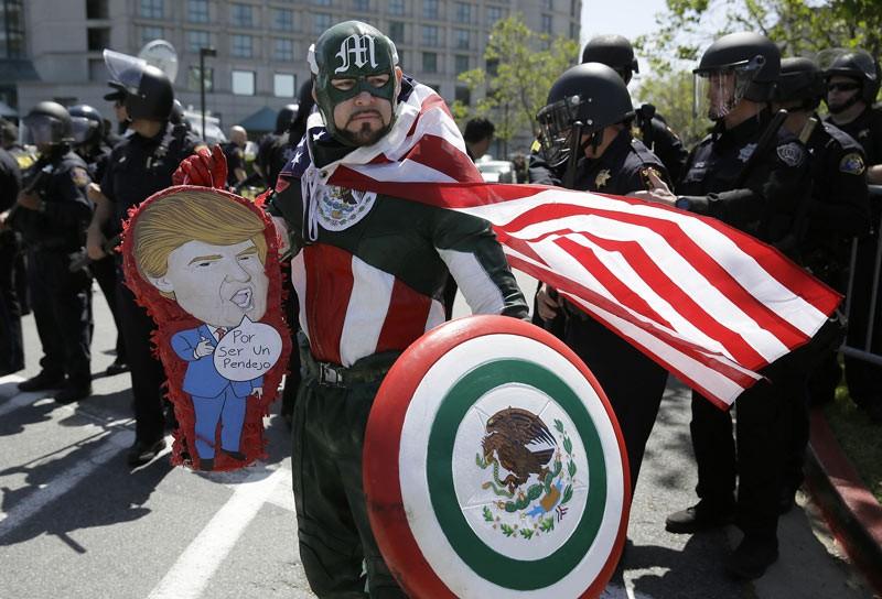 Erik Lopez, dressed as “Captain Mexico,” stands in front of police officers while protesting Republican presidential candidate Donald Trump outside of the Hyatt Regency hotel during the California Republican Party 2016 Convention. (Eric Risberg / AP)