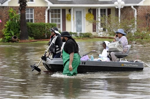 Volunteers pull a boat with a woman and young child as they evacuate from their homes Saturday, Aug. 13, 2016, in Baton Rouge. Louisiana Gov. John Bel Edwards says more than 1,000 people in south Louisiana have been rescued from homes, vehicles and even clinging to trees as a slow-moving storm hammers the state with flooding. (John Oubre |The Advocate via AP)