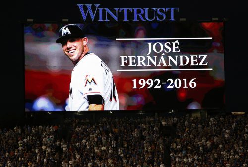 Baseball fans stand for a minute of silence for Miami Marlins pitcher Jose Fernandez, who was killed early Sunday, Sept. 25, 2016 in a boating accident in Miami, before a baseball game between the St. Louis Cardinals and the Chicago Cubs Sunday, Sept. 25, 2016, in Chicago. (AP Photo/Nam Y. Huh)