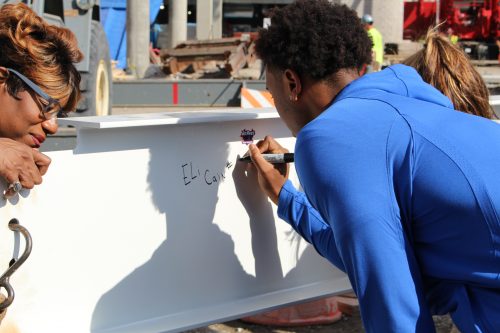 Sophomore guard Eli Cain signs his name on the final beam to be put up in the new DePaul arena on Oct. 5. (Jack Higgins/The DePaulia)