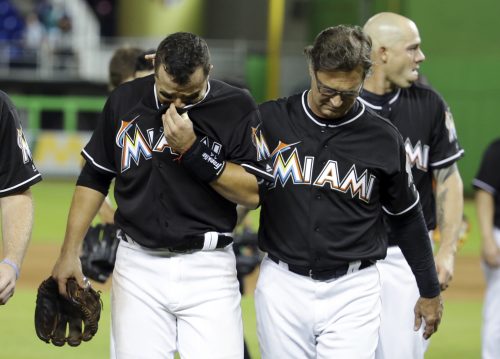 Miami Marlins' Martin Prado, left, walks off the field with manager Don Mattingly, right, after a baseball game against the New York Mets, Monday, Sept. 26, 2016, in Miami. The Marlins defeated the Mets 7-3. The Marlins pitcher Jose Fernandez was honored during the game. Fernandez was killed in a boating accident early Sunday. (AP Photo/Lynne Sladky)