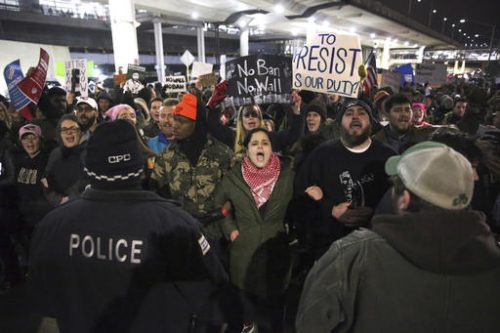 Protesters gather at O'Hare International Airport after more than a dozen people were detained, including green card holders, Saturday, Jan. 28, 2017, in Chicago. They were detained following President Donald Trump's executive order on Friday that bans legal U.S. residents and visa-holders from seven Muslim-majority nations from entering the U.S. for 90 days and puts an indefinite hold on a program resettling Syrian refugees.  (Chris Sweda/Chicago Tribune via AP)