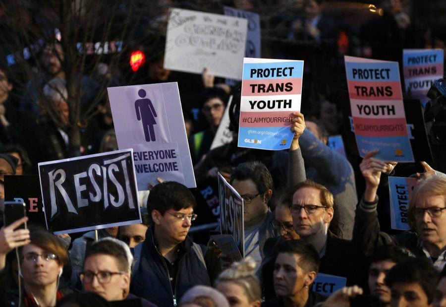 Protesters hold signs at a rally in support of transgender youth, Thursday, Feb. 23, 2017, at the Stonewall National Monument in New York. They were demonstrating against President Donald Trump's decision to roll back a federal rule saying public schools had to allow transgender students to use the bathrooms and locker rooms of their chosen gender identity. The rule had already been blocked from enforcement, but transgender advocates view the Trump administration action as a step back for transgender rights. (AP Photo/Kathy Willens)