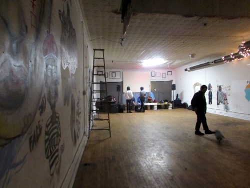 Artists walk the empty apartment as others set their speakers and equipment up before guests arrive at the D.I.Y. music venue for the concert. (Molly O'Mera / The DePaulia)