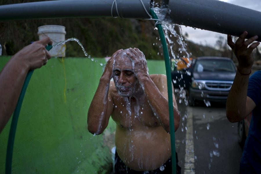 People affected by Hurricane Maria bathe in water piped from a creek in the mountains, in Naranjito, Puerto Rico, Thursday, Sept. 28, 2017. Residents of the area drive to the pipes to bathe because they were left without water supplies by the damage caused by Hurricane Maria. The pipe was set up by a neighbor who ran it from a creek in his property to the side of the road in order to help those left without water. (AP Photo/Ramon Espinosa)