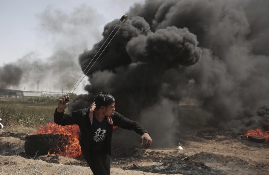 A Palestinian protester hurls stones at Israeli troops during a massive protest that happened on April 6 at the Gaza Strips border.
(Khalil Hamra | AP)