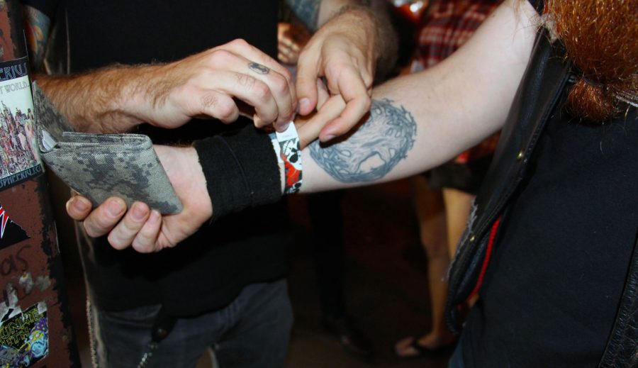 Chris Pluska, a security guard at Reggie’s Rock Club, places a 21+ drinking wristband on a patron.