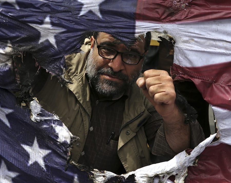 An Iranian protestor clenches his fist behind a burnt representation of the U.S. flag during a gathering after their Friday prayer in Tehran, Iran on May 11, 2018. Thousands of Iranians took to the streets in cities across the country to protest U.S. President Donald Trumps decision to pull out of the nuclear deal with world powers. 