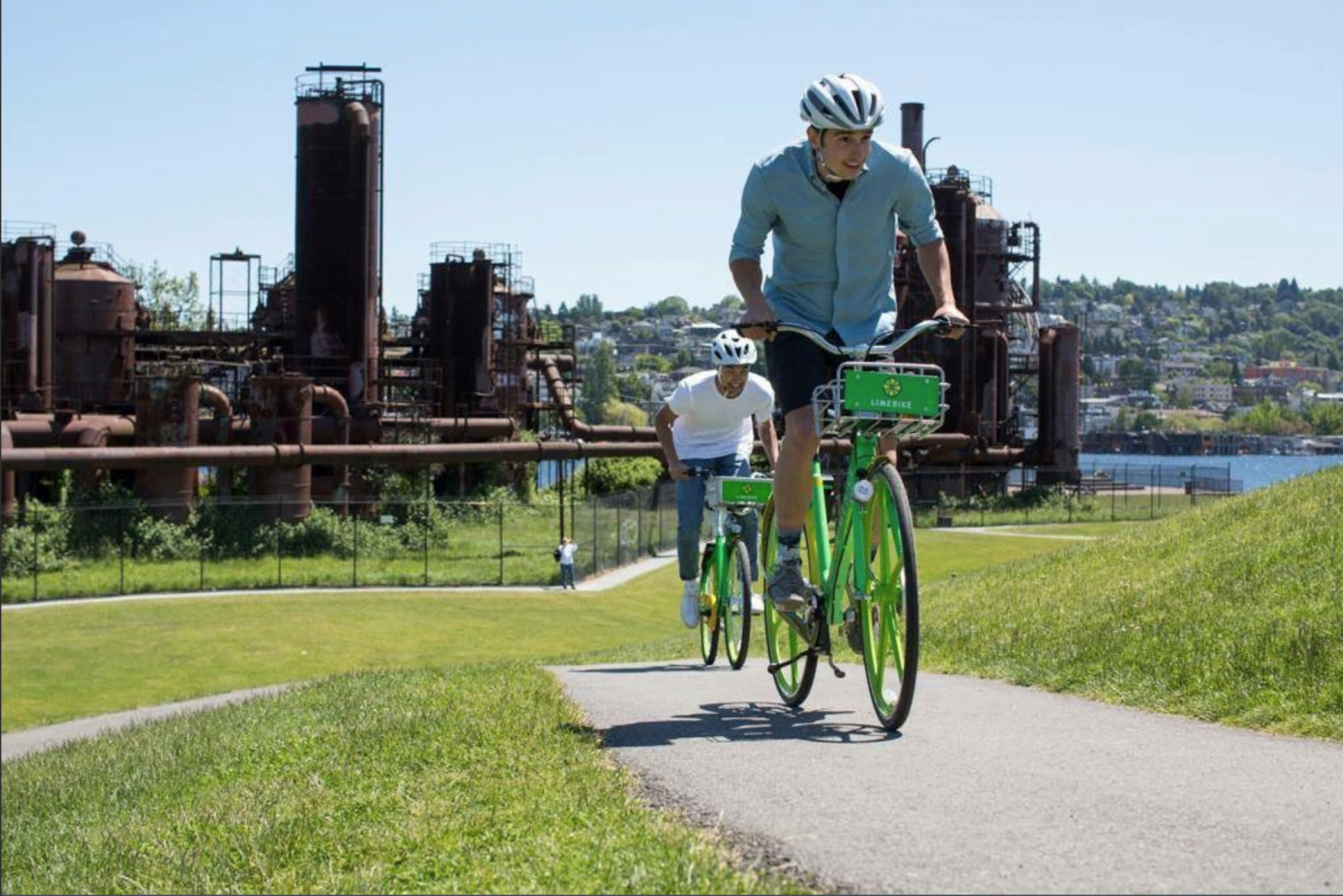 People riding LimeBikes past a rusted plant in Seattle, Washington. Seattle is one of many cities in U.S. who adopted dockless bike sharing.