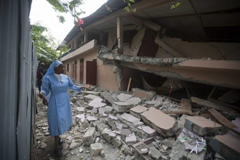 Sr Maryse Alsaint walks alongside a school damaged by a magnitude 5.9 earthquake the night before, in Gros Morne, Haiti, Sunday, Oct. 7, 2018. Emergency teams worked to provide relief in Haiti on Sunday after the quake killed at least 11 people and left dozens injured.