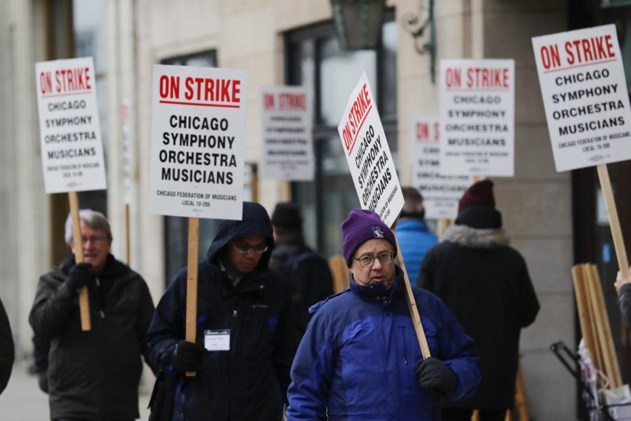 In this Monday, March 11, 2019 file photo, striking Chicago Symphony Orchestra musicians walk the picket line outside of Symphony Center in Chicago. On Saturday, April 27, 2019, negotiators for the Chicago Symphony Orchestra and musicians said they have reached an agreement to end the seven-week strike.