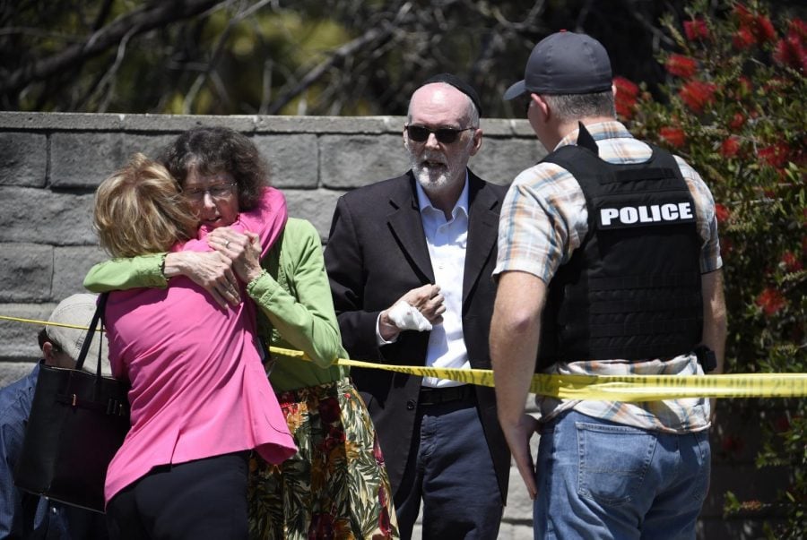 Two people hug as another talks to a San Diego County Sheriffs deputy outside of the Chabad of Poway Synagogue Saturday, April 27, 2019, in Poway, Calif. Several people have been shot and injured at a synagogue in San Diego, California, on Saturday, said San Diego County authorities.