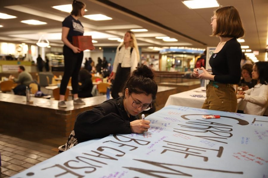 Vanessa Garcia, a freshman secondary education and English major, signs a poster expressing her support for victims of sexual abuse.